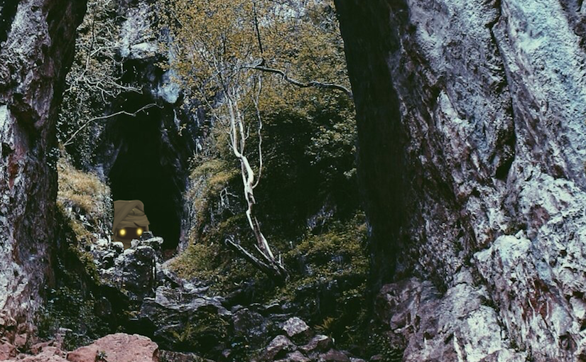 A GOBLIN is peaking out of a cave.